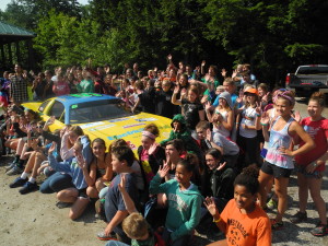 Campers from Camp Susan Curtis surround the Electricity Maine #6 car during a recent visit to the camp.