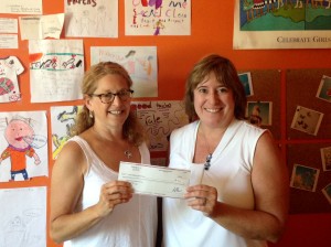 Julie Lapham (L) of ENH Power, presents Kathy Beebe (R) of SASS with a check from  the Power to Help Fund, a program implemented by ENH Power to help local non-profits. SASS plans to use the money to educate and raise awareness in schools in the area. 