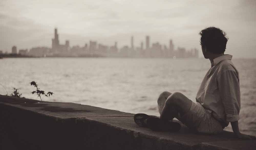 Man sitting on wall looking at cityscape