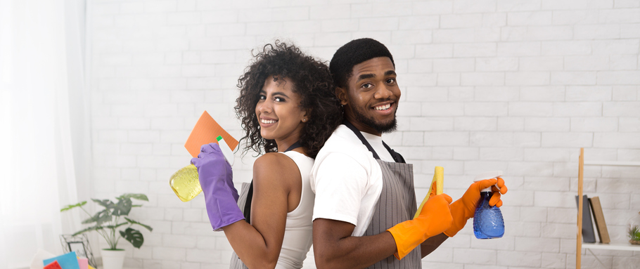 Happy couple holding detergents during cleaning at home